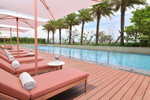 A poolside area with sun loungers and umbrellas, surrounded by palm trees and a clear sky. - Le Mã©ridien Hualien Resort (Hualien City)