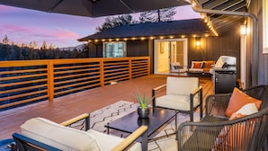 Une terrasse dotée de mobilier d’extérieur, d’un barbecue et offrant une vue sur le paysage environnant.