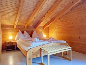 Un dormitori de cabana de fusta amb un llit, almoines, una taula de nit i una meseta de nit.