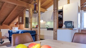 Un intérieur chaleureux, avec des éléments en bois, une table à manger, des chaises et un panier de fruits.