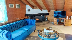 Un salon chaleureux avec un canapé bleu, une cheminée, un téléviseur et des étagères en bois.