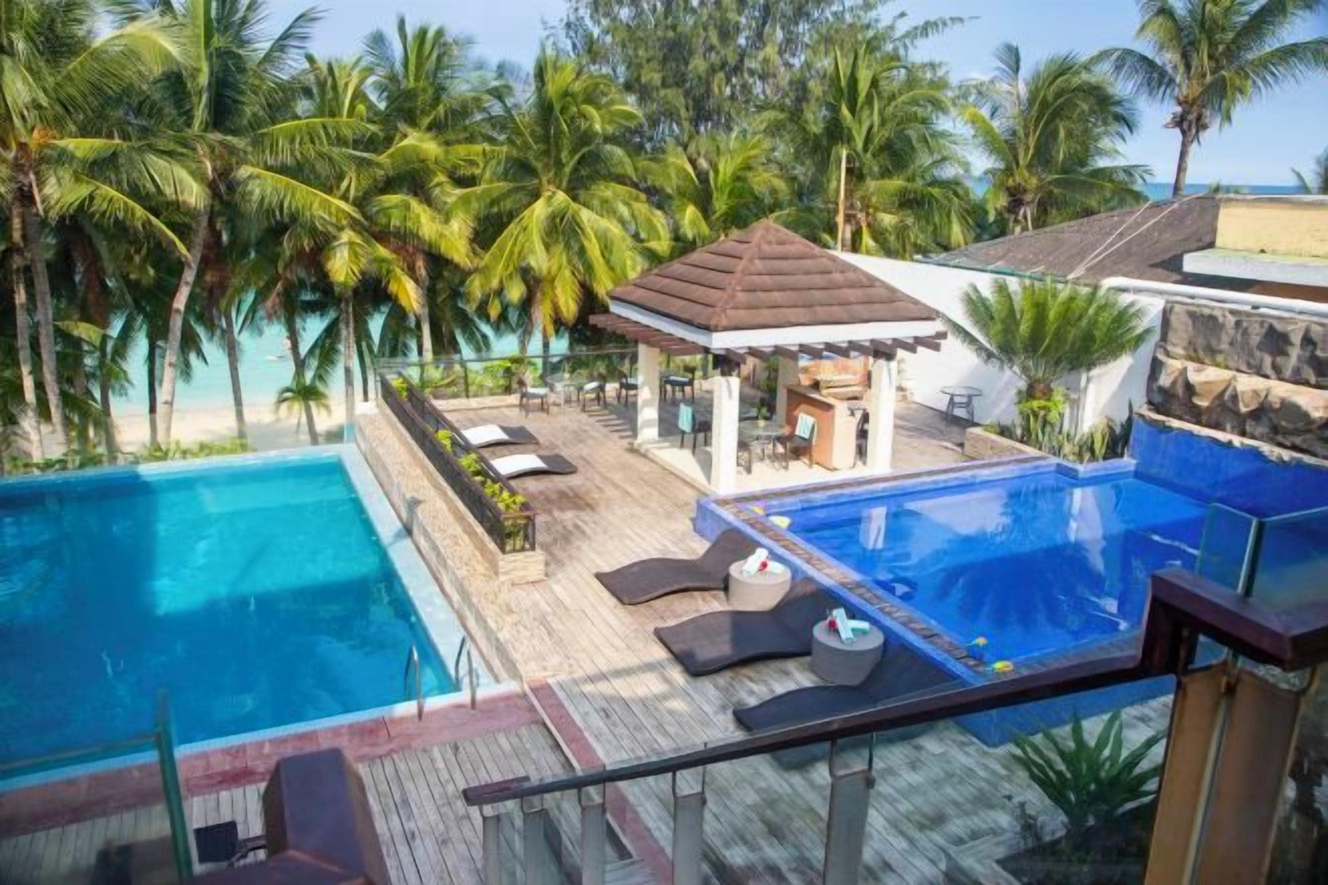 Ein Poolbereich mit Liegestühlen und einem Gazebo mit Blick auf einen Strand.