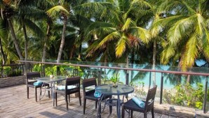 A wooden deck with tables and chairs, surrounded by palm trees. - Crown Regency Beach Resort (Boracay Island)