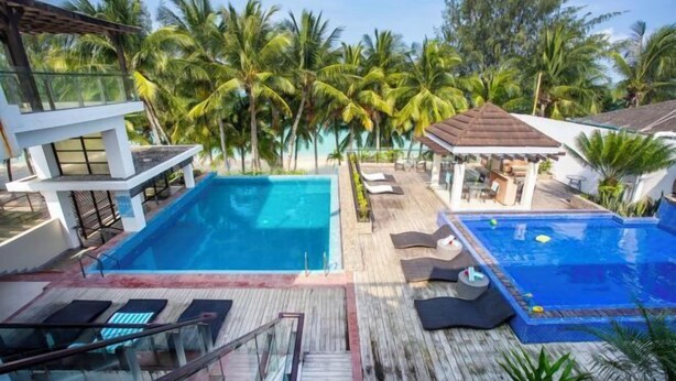 A rooftop pool area with two separate pools, lounge chairs, and a wooden deck. - Crown Regency Beach Resort (Boracay Island)