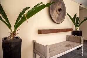 A room with a wooden bench, two potted plants, and a wooden wall decoration. - Crown Regency Beach Resort (Boracay Island)