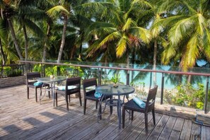An outdoor deck with tables and chairs, surrounded by palm trees. - Crown Regency Beach Resort (Boracay Island)