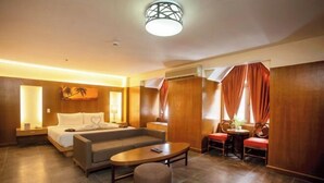A hotel room with a bed, sofa, coffee table, and a small dining area. - Crown Regency Beach Resort (Boracay Island)