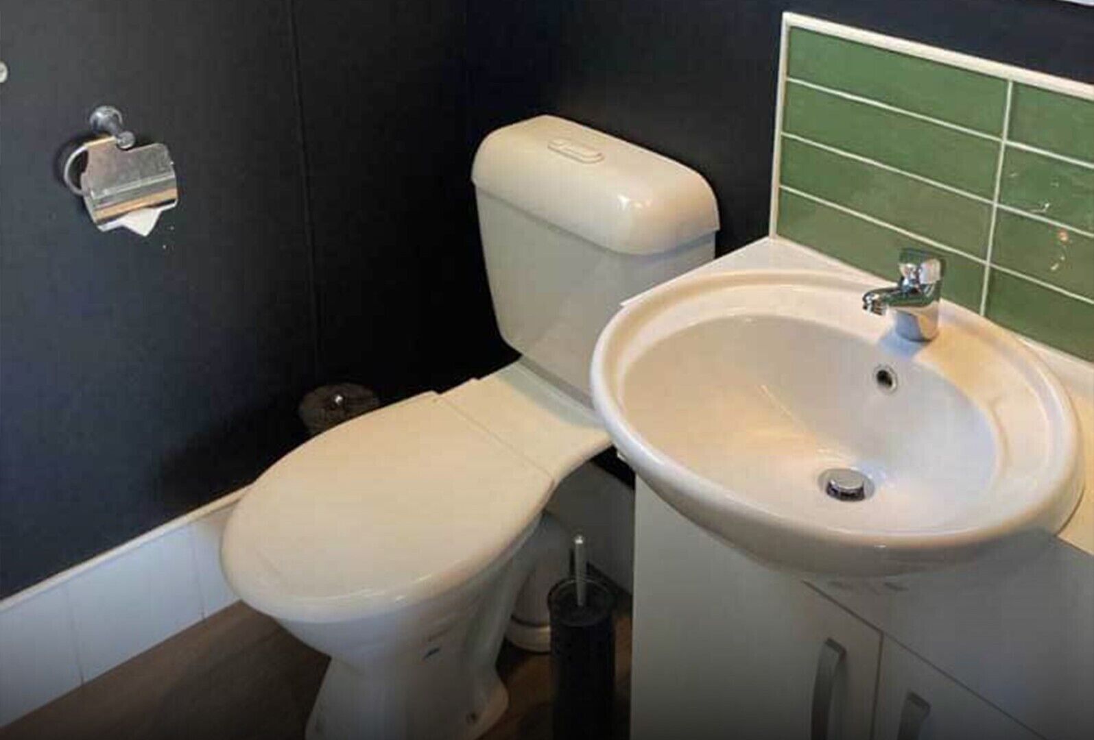A bathroom with a toilet, sink, and a trash bin.