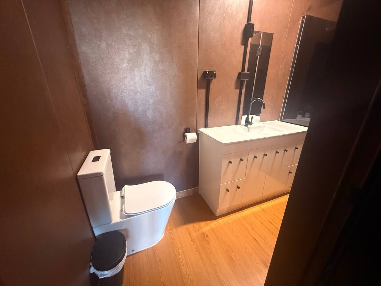 A compact bathroom with a toilet, sink, and cabinet.