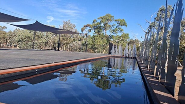 A pool with a clear reflection, surrounded by trees and a shaded area. - Stawell Grampians Gate C & C Park (Stawell)