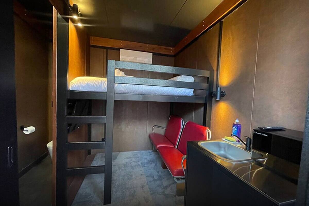 Habitación con literas, escritorio, silla, inodoro y lavamanos.