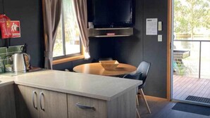 A modern kitchen with a central island, a dining table, and a TV mounted above. - Stawell Grampians Gate C & C Park (Stawell)