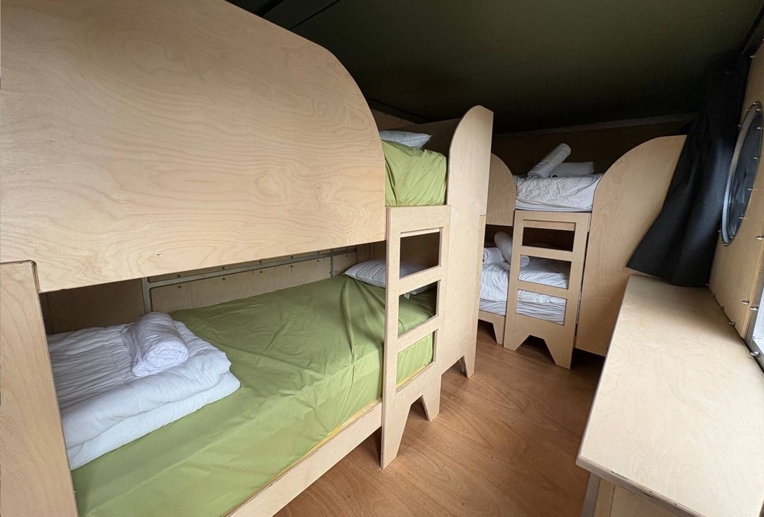 A bunk bed room with a desk and a small shelf.