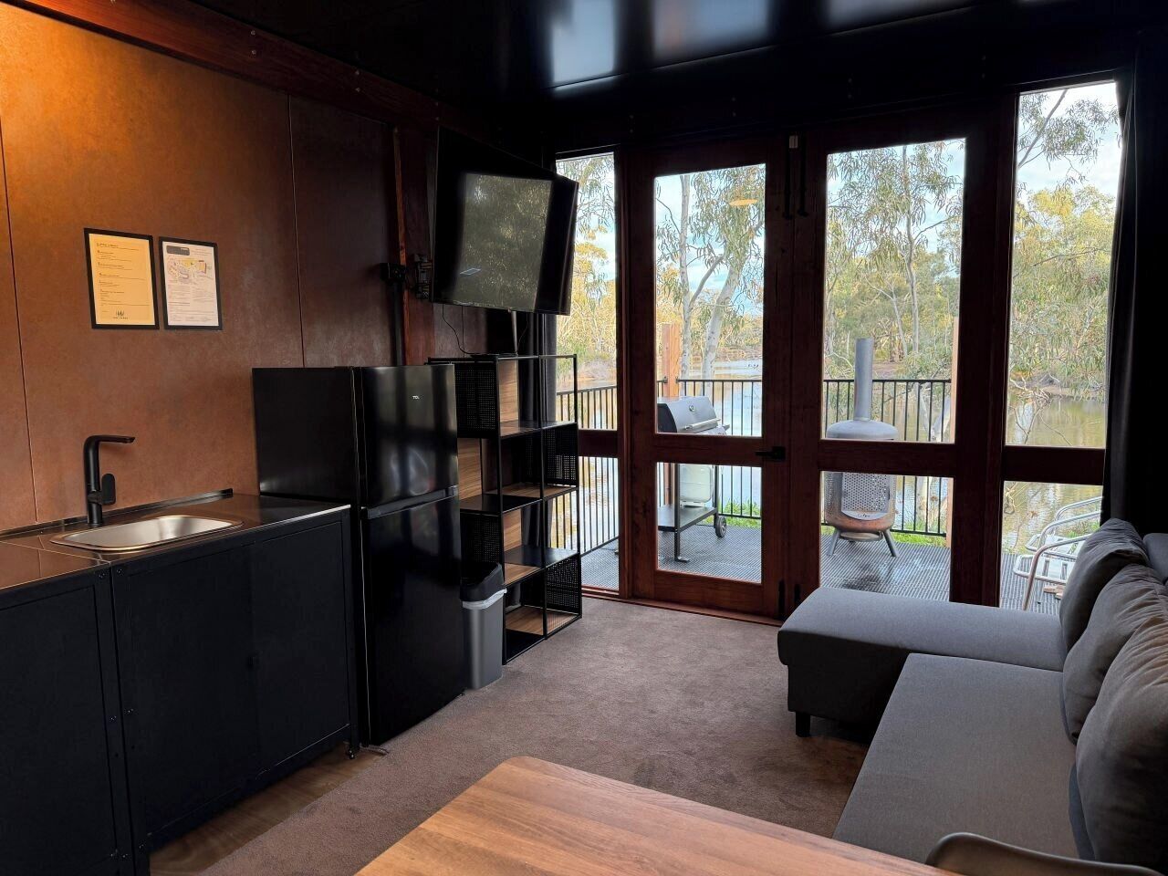 A modern kitchen with a built-in TV, a dining area with a sofa, and a view of the outdoors.