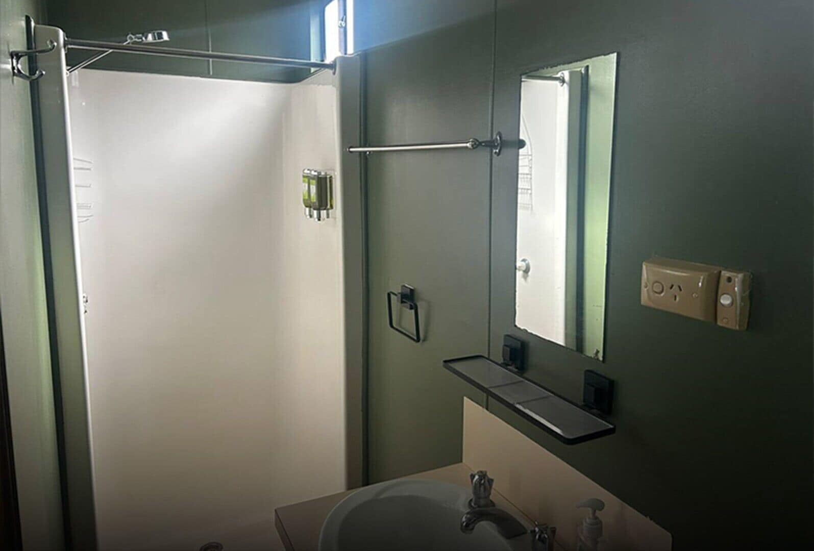 A bathroom with a shower, sink, mirror, and towel rack.