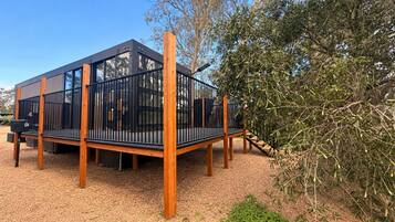 Una terraza moderna al aire libre con baranda de metal, postes de madera y cobertura de grava.