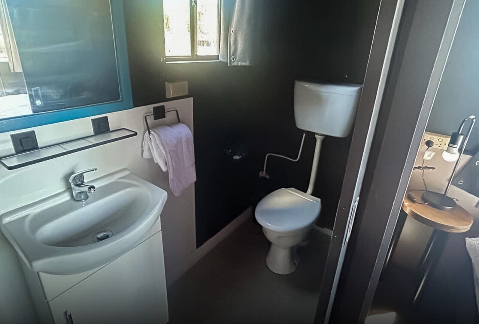 Un baño pequeño con lavabo, inodoro y un ventanal.