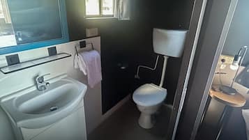 Un baño pequeño con lavabo, inodoro y un ventanal.