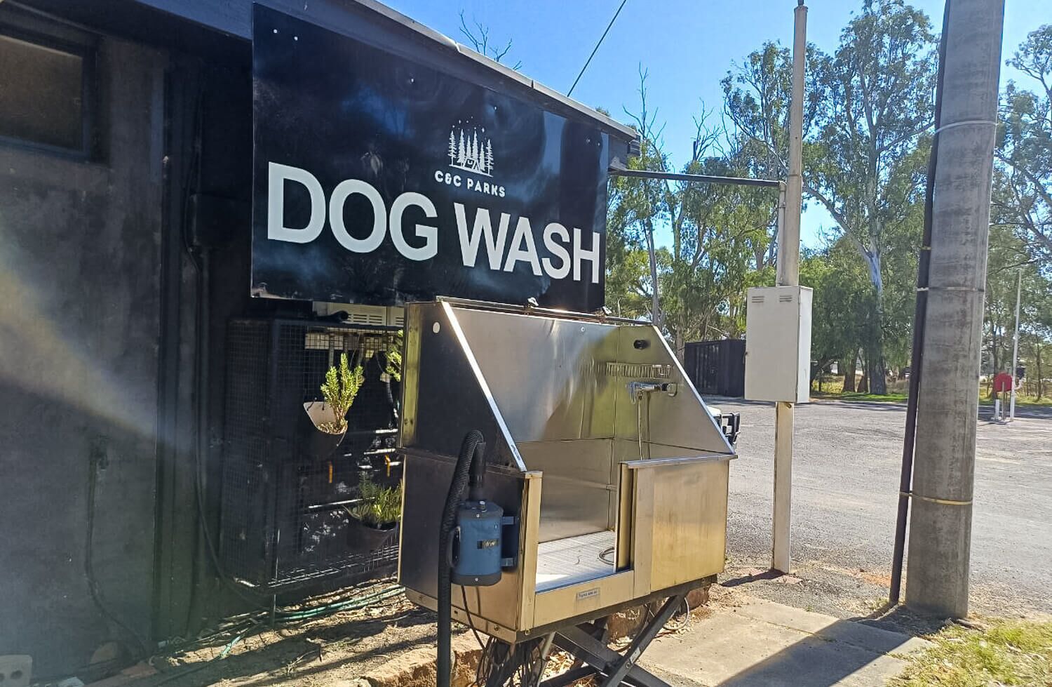 A portable dog wash station with a sign reading 'DOG WASH' and a logo for 'CCC PARKS'.
