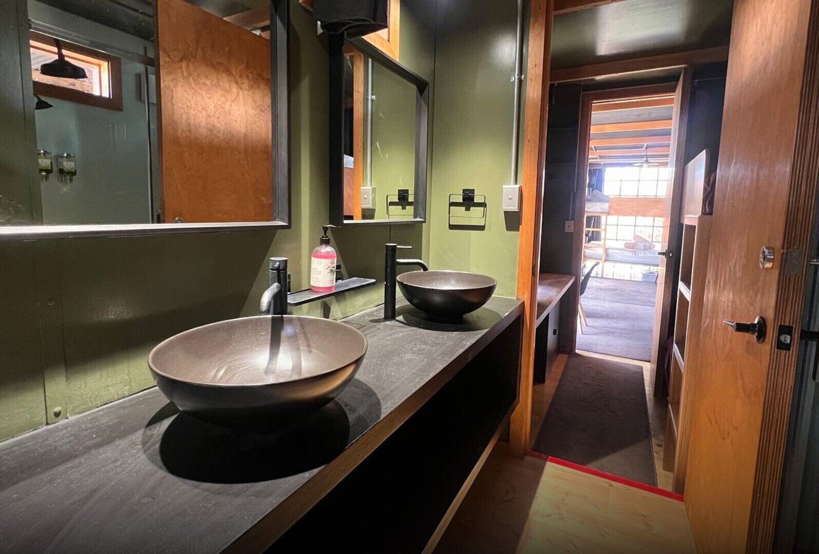 Un baño con dos lavamanos grandes, un espejo y una puerta de madera.