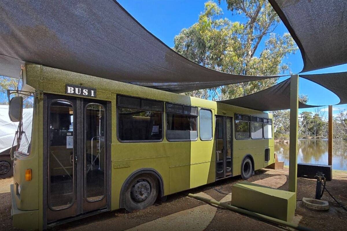 Un autobús verde con la inscripción 'BUSI' estacionado bajo una marquesina.