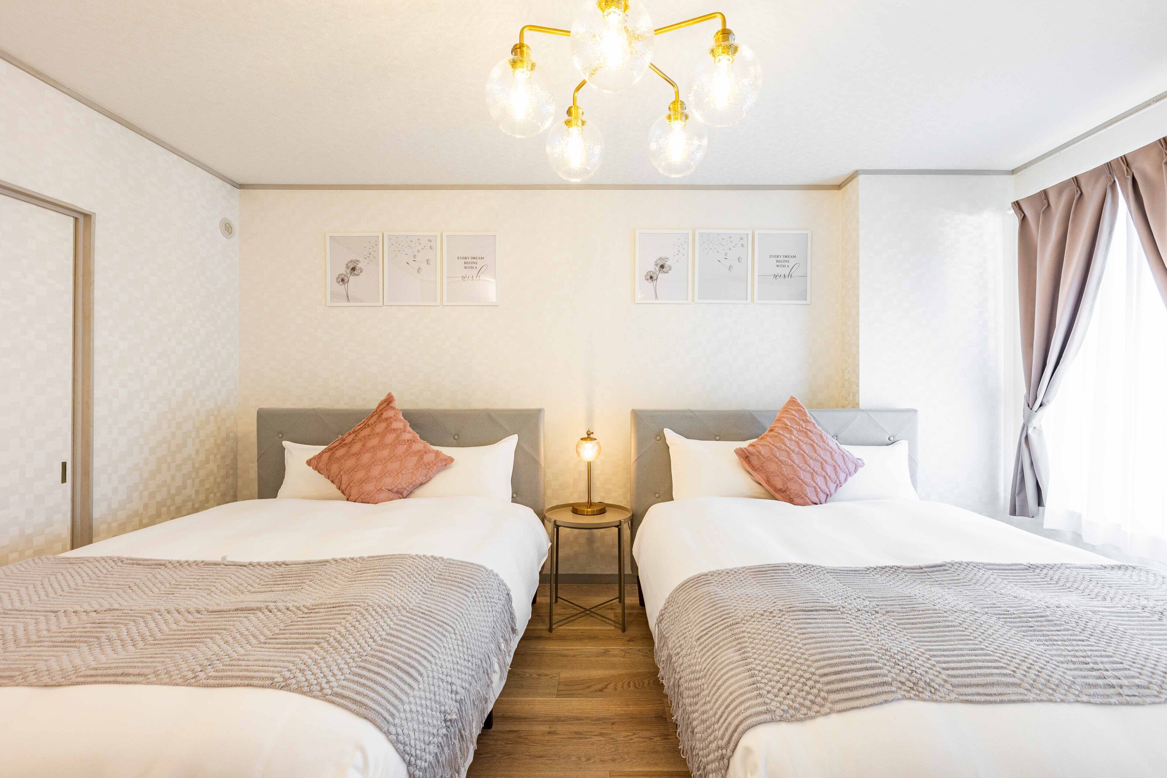 Una camera d'albergo con due letti, un lampadario, opere d'arte incorniciate sulla parete e un comodino con una lampada.