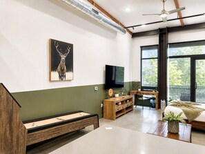 A modern living room with a wooden bench, a television, and a large window. - Dog Friendly DTSA Loft 5 Miles to Disney w/ Gym (Santa Ana)