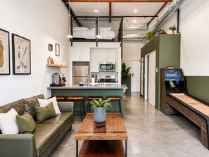 Un interior moderno con un sofá, una mesa de centro, una zona de cocina y una mesa de ping pong.