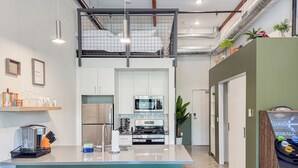 Una cocina moderna con una isla central, taburetes de bar, microondas y cafetera.