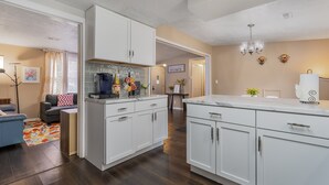 A modern kitchen with white cabinets, a marble countertop, and a chandelier. - Comfy, Convenient, and Charm 3BR Retreat near BGSU (Bowling Green)