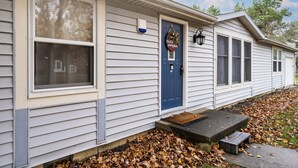 A house with a blue front door, a welcome sign, and a small porch with a bench. - Comfy, Convenient, and Charm 3BR Retreat near BGSU (Bowling Green)