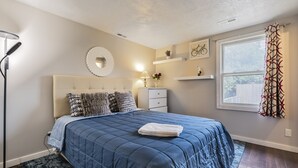 A bedroom with a bed, bedside table, lamp, and a window with curtains. - Comfy, Convenient, and Charm 3BR Retreat near BGSU (Bowling Green)