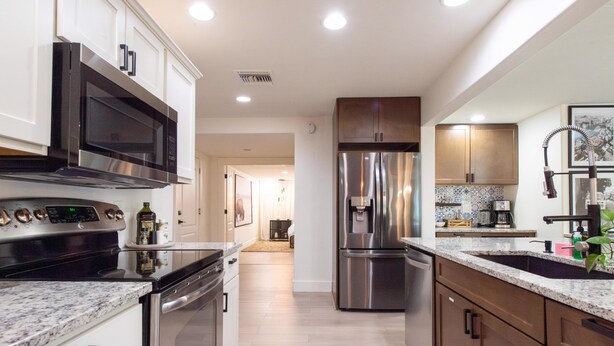 A modern kitchen with stainless steel appliances, wooden cabinets, and a granite countertop. - Monte Horizon Oasis by HomeSlice Stays (Phoenix)
