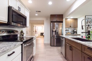 A modern kitchen with stainless steel appliances, wooden cabinets, and a granite countertop. - Monte Horizon Oasis by HomeSlice Stays (Phoenix)