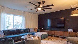 A modern living room with a sectional sofa, a coffee table, and a flat-screen TV mounted on the wall. - Monte Horizon Oasis by HomeSlice Stays (Phoenix)