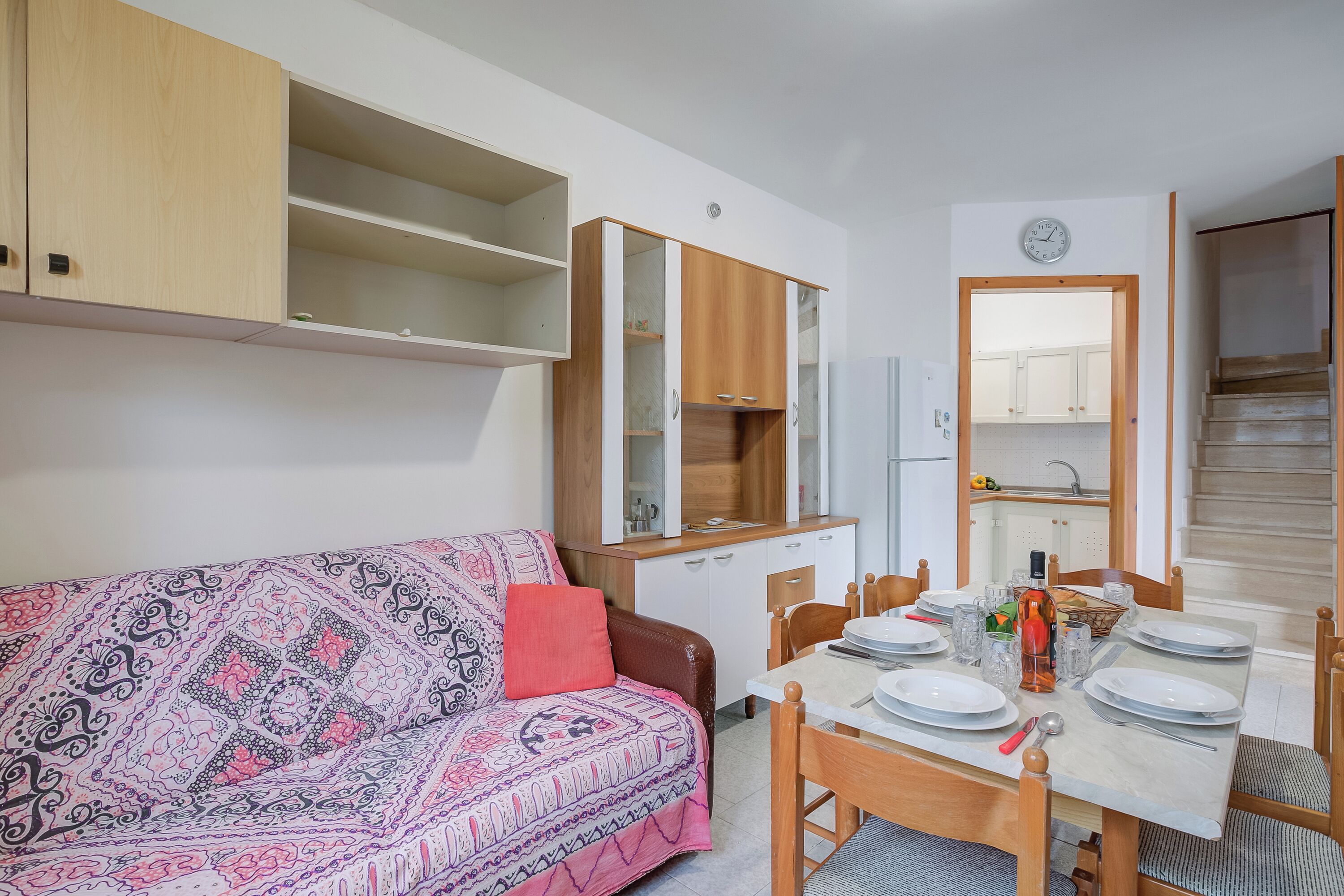 Un espacio habitable pequeño con sofá, mesa de comedor y armarios empotrados.
