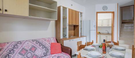 Un espacio habitable pequeño con sofá, mesa de comedor y armarios empotrados.