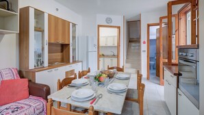 Um espaço compacto com área de refeições, kitchenette e um pequeno espaço para sentar.