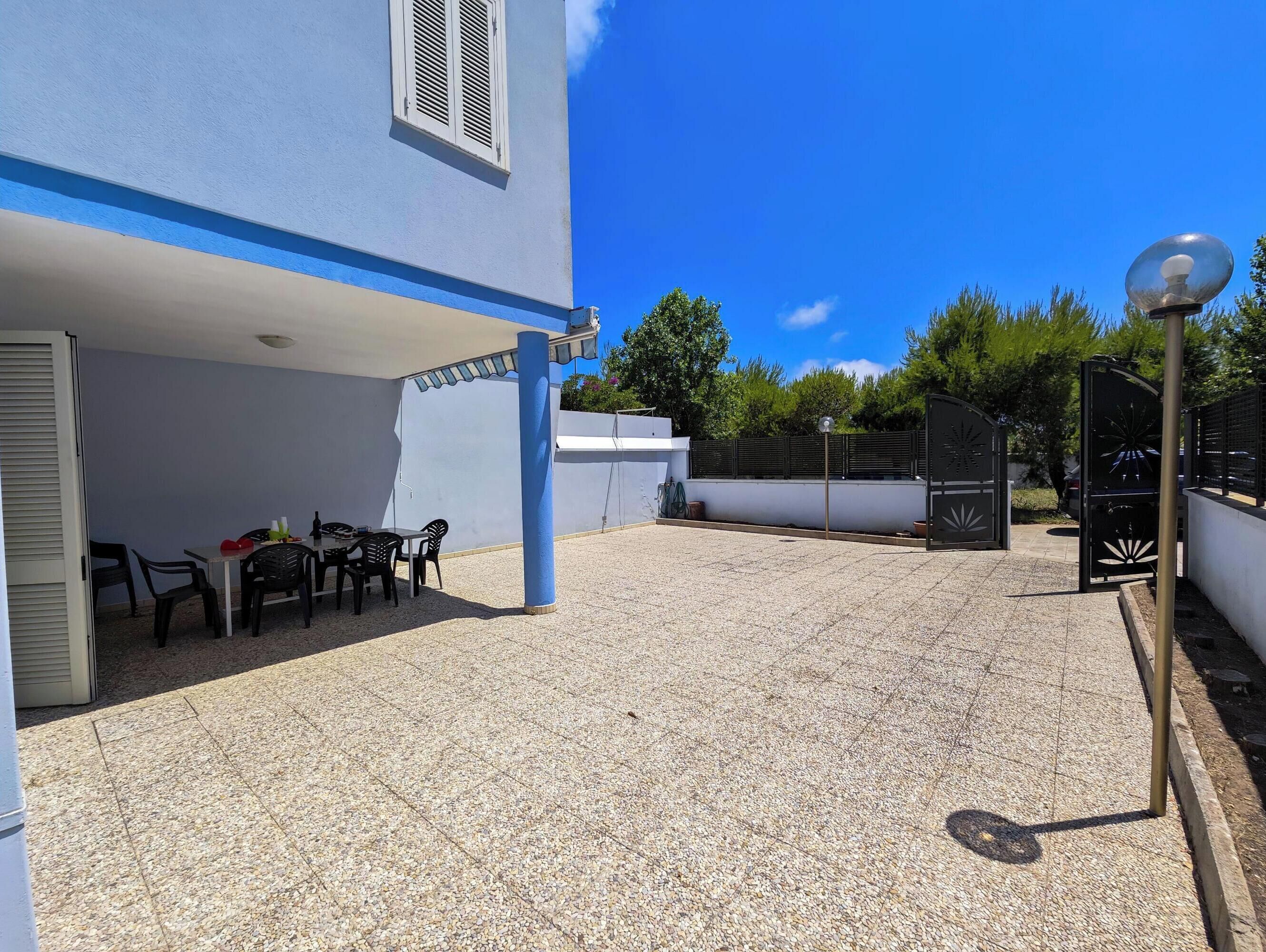Un espacio al aire libre cubierto con una mesa, sillas, una pérgola y una valla decorativa.