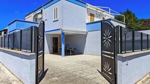 Um edifício de dois andares com fachada azul, um espaço de varanda coberto e uma entrada com portão.