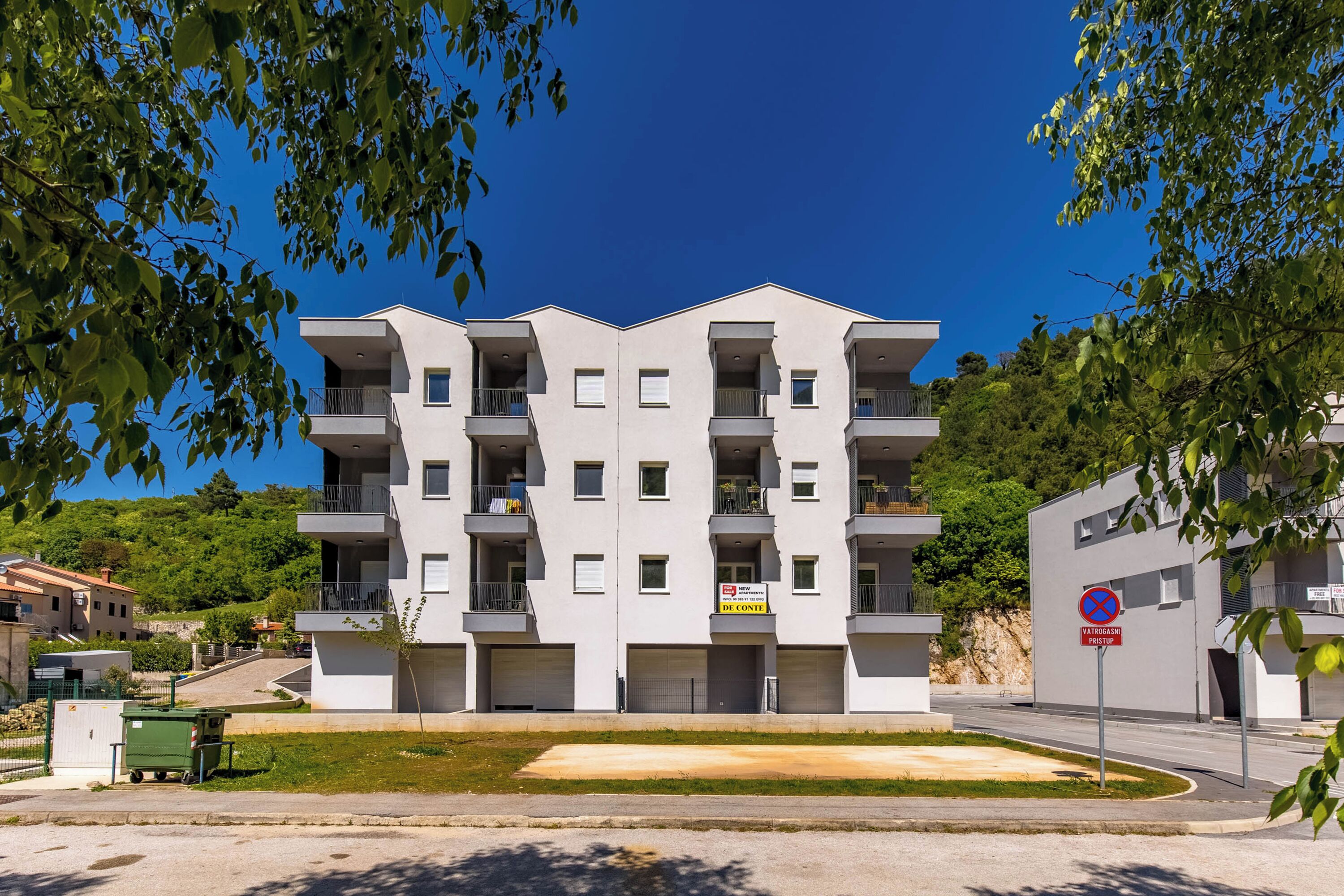 Un immeuble résidentiel à plusieurs étages, doté de balcons, d’un espace de stationnement et d’un panneau indiquant qu’il est interdit de se garer.