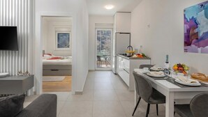 A modern apartment with a dining area, kitchenette, and a TV mounted on the wall. - Seafront Villa Andrijana (Krsan)
