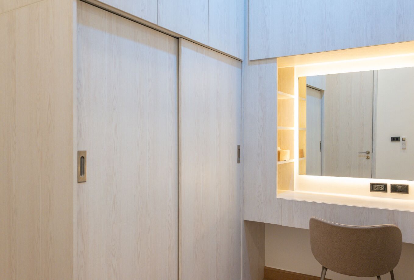 A modern bathroom with a vanity, mirror, and a chair.