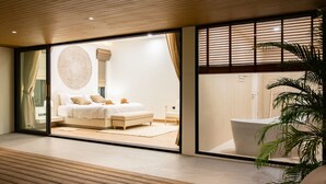 A modern bedroom with a large bed, a round wall decoration, and a view of a bathroom through a glass door. - Villa Close to Fisherman Village - KBR15 (Koh Samui)