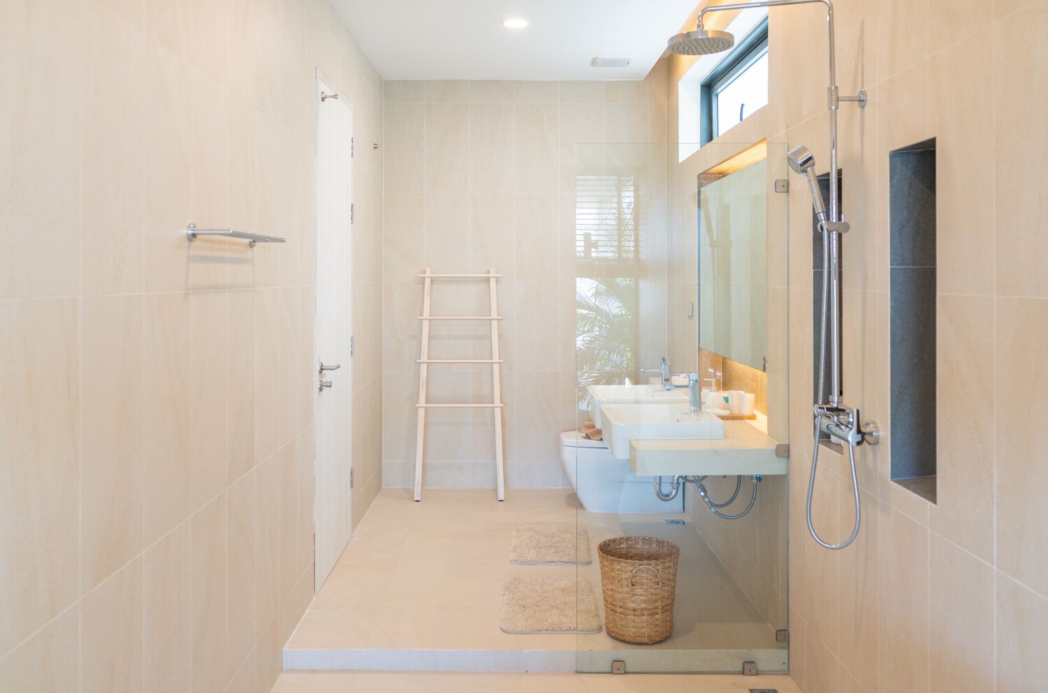 A modern bathroom with a walk-in shower, two sinks, a toilet, and a ladder.