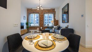Un coin repas avec un mur en briques, un lustre et une table à manger moderne, mise pour quatre personnes.