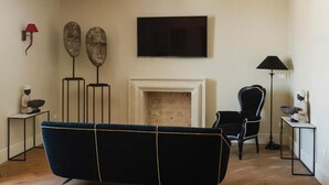 Un salon comprenant un canapé, une cheminée, un téléviseur et deux éléments décoratifs fixés au mur.