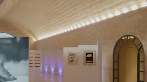Une galerie d’art avec un plafond haut et un mur en briques.