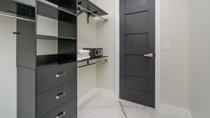 Un armario moderno con repisas negras, una puerta blanca y un piso de mármol.