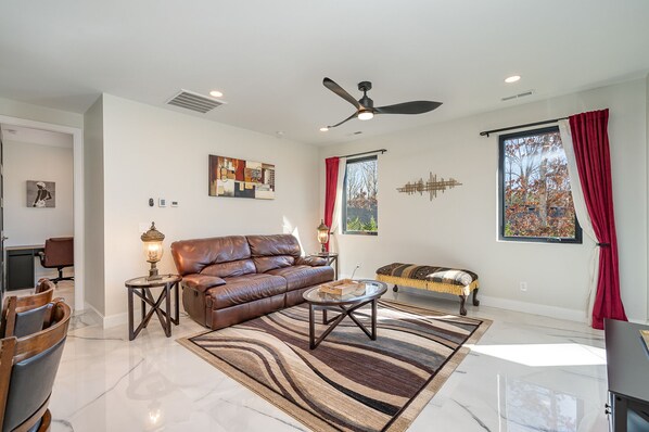 A modern living room with a brown leather sofa, a glass coffee table, and a patterned rug. - All New spacious cozy in-law suite 1BD minutes to highway 485 & 74 (Matthews)